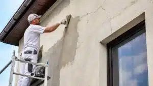 Réparation de fissures sur une façade de maison avec application d’un enduit extérieur